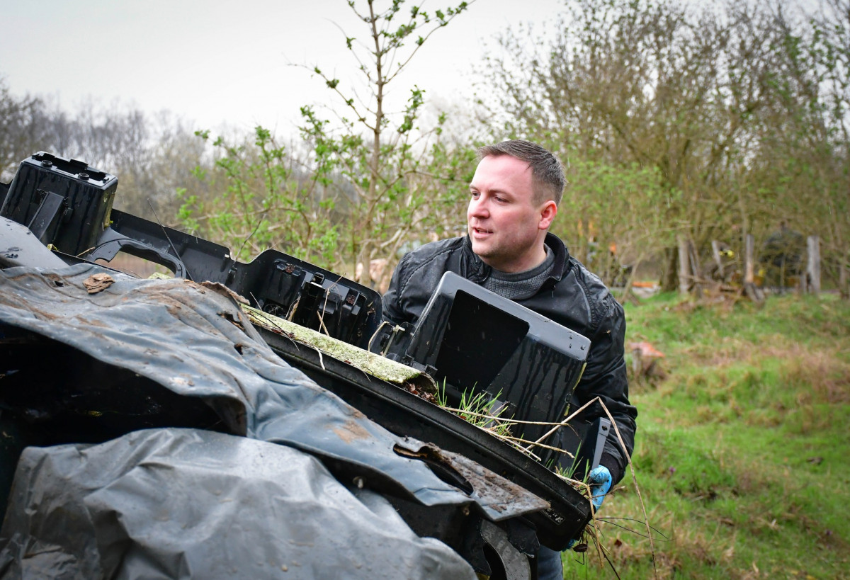 Türk László képviselő egy nagyobb darab hulldékot helyez konténerbe a Nagycserei Erdő tisztítása közben